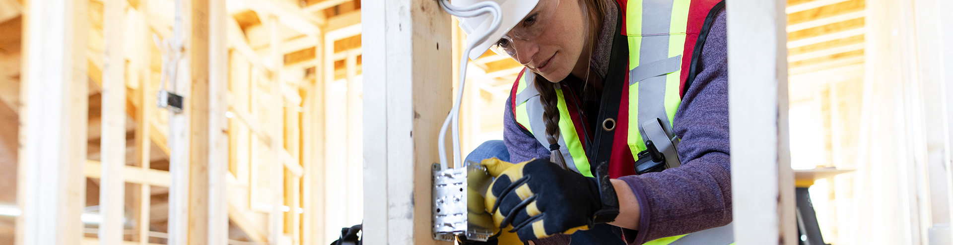 female electrician wiring an electrical outlet in a new build