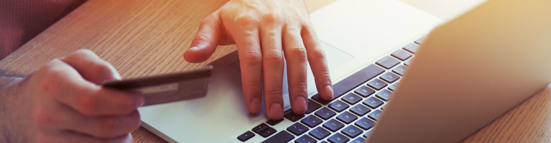hand holding a credit card using a laptop