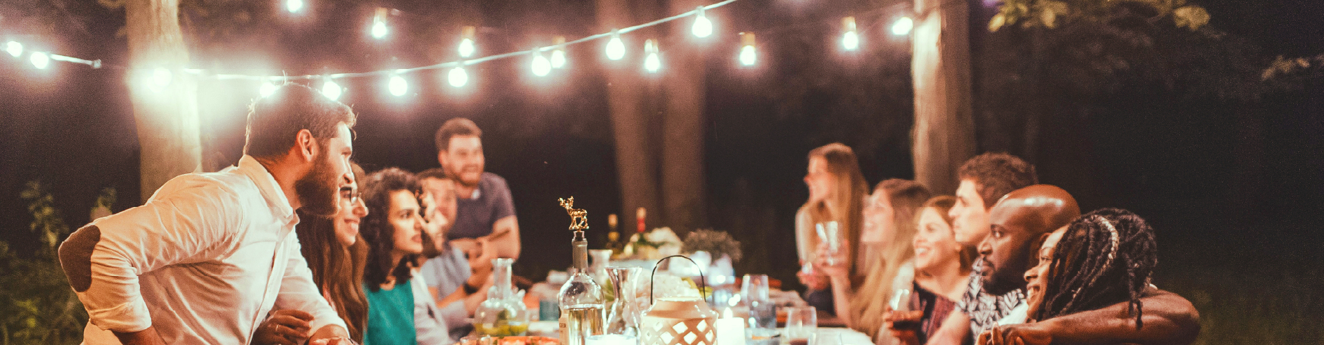people sitting around a table in a lit up garden